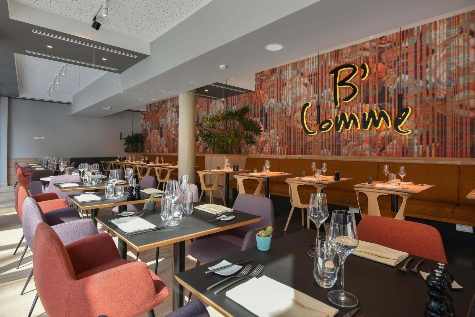 Modern restaurant dining space with colorful brick wall artwork and contemporary furnishings.
