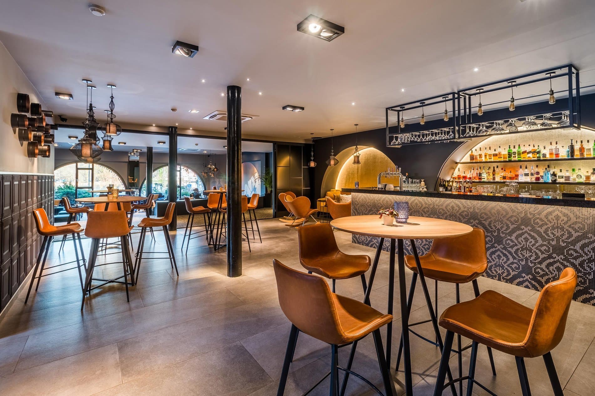 Modern bar and lounge area with orange seating, gold lighting, and contemporary hospitality design.