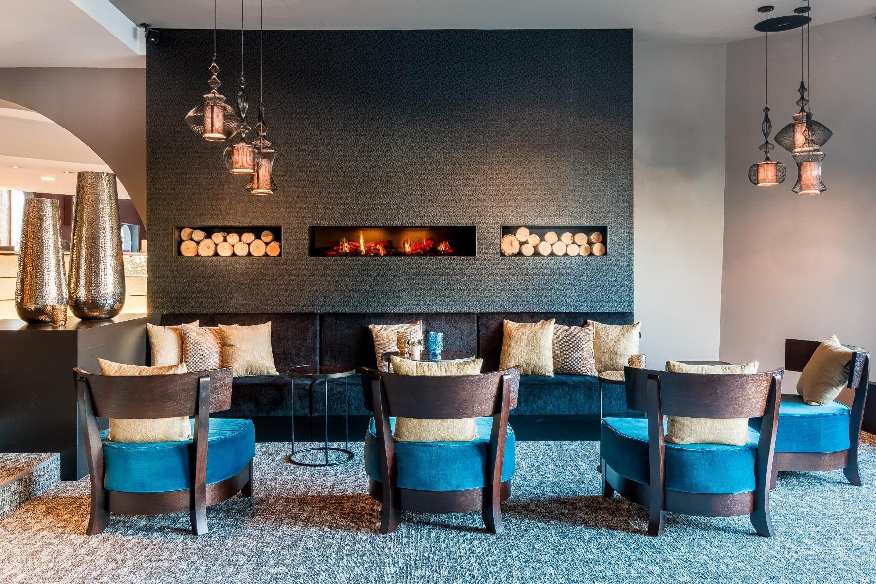 Luxurious lounge with fireplace, pendant lighting, and contemporary seating arrangements.