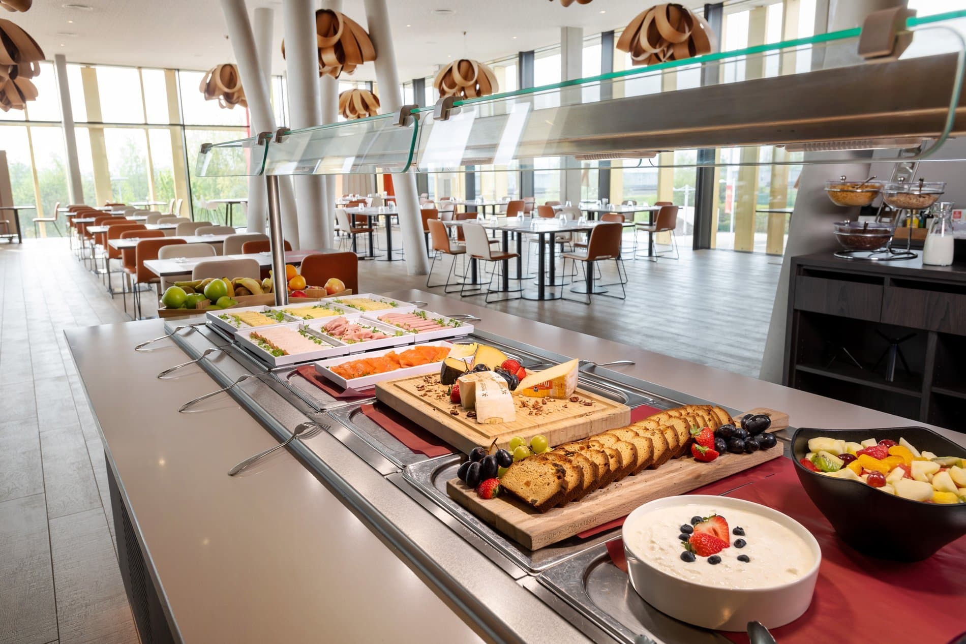 Modern breakfast buffet with charcuterie, bread, and fruits in contemporary dining space