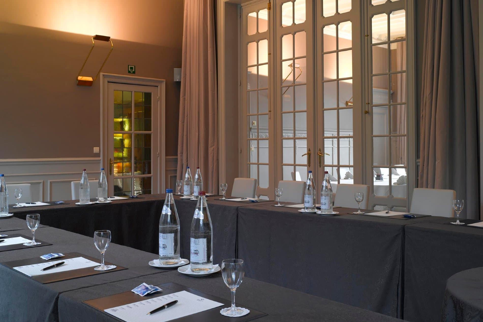 Elegant conference or dining room with panoramic windows overlooking outdoor landscape.