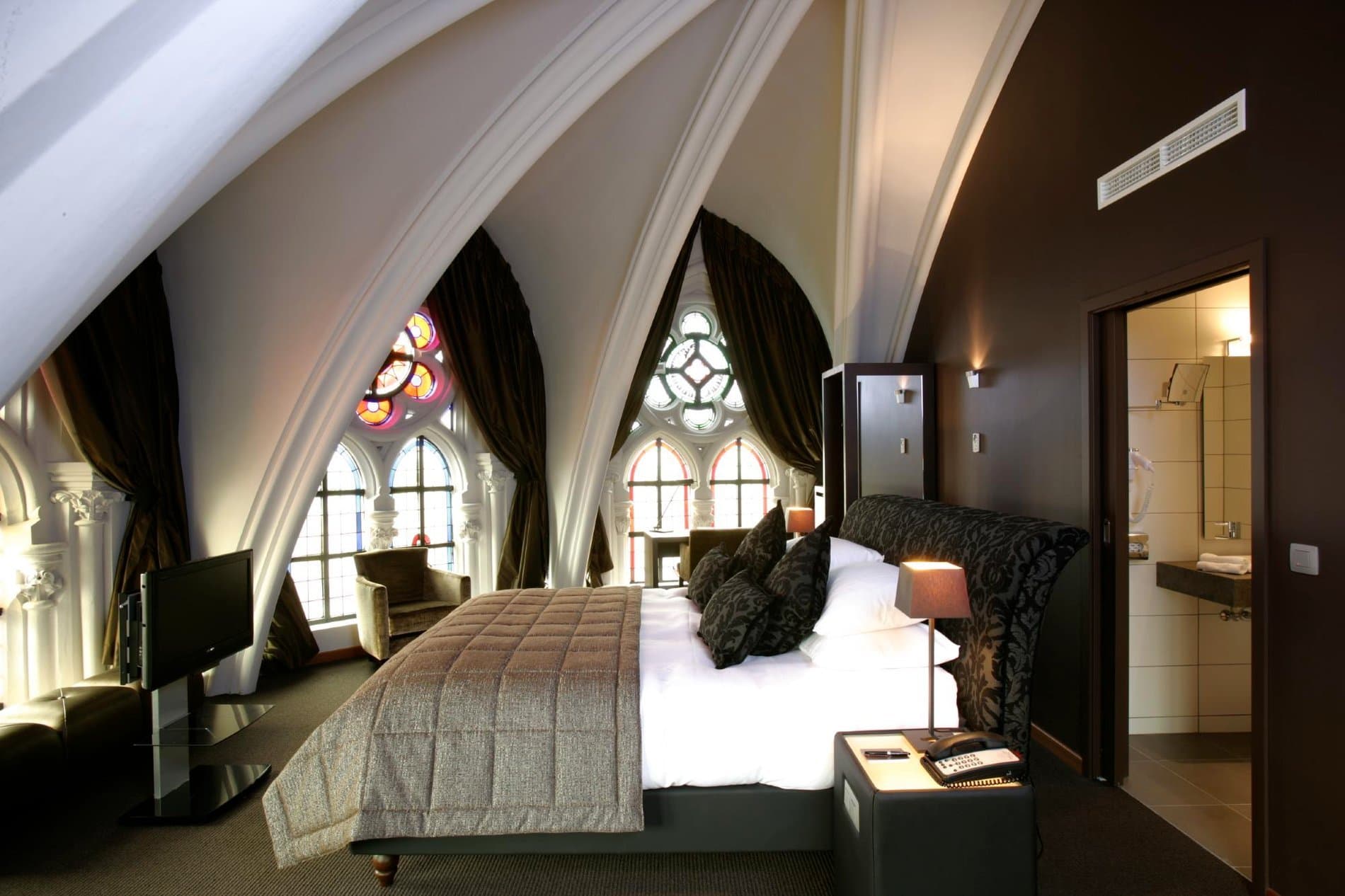 Luxury bedroom suite with stained glass arches, ensuite bathroom, and dramatic architectural features.