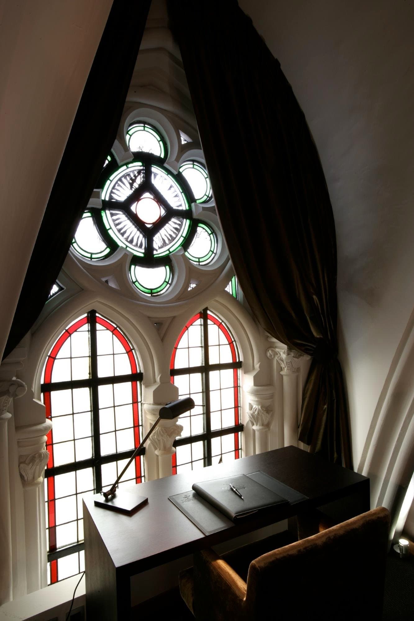 Historic workspace nook with stained glass windows and ornate architectural details overhead.