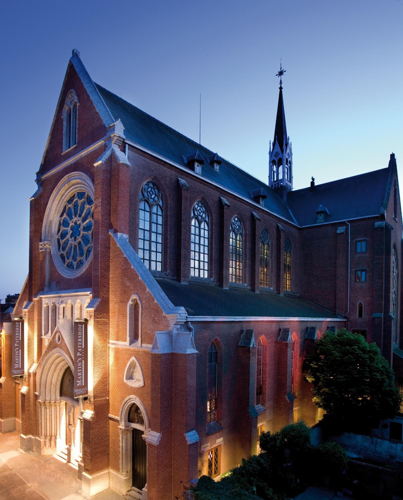 Historic red brick chapel exterior with stained glass windows and illuminated facade at twilight