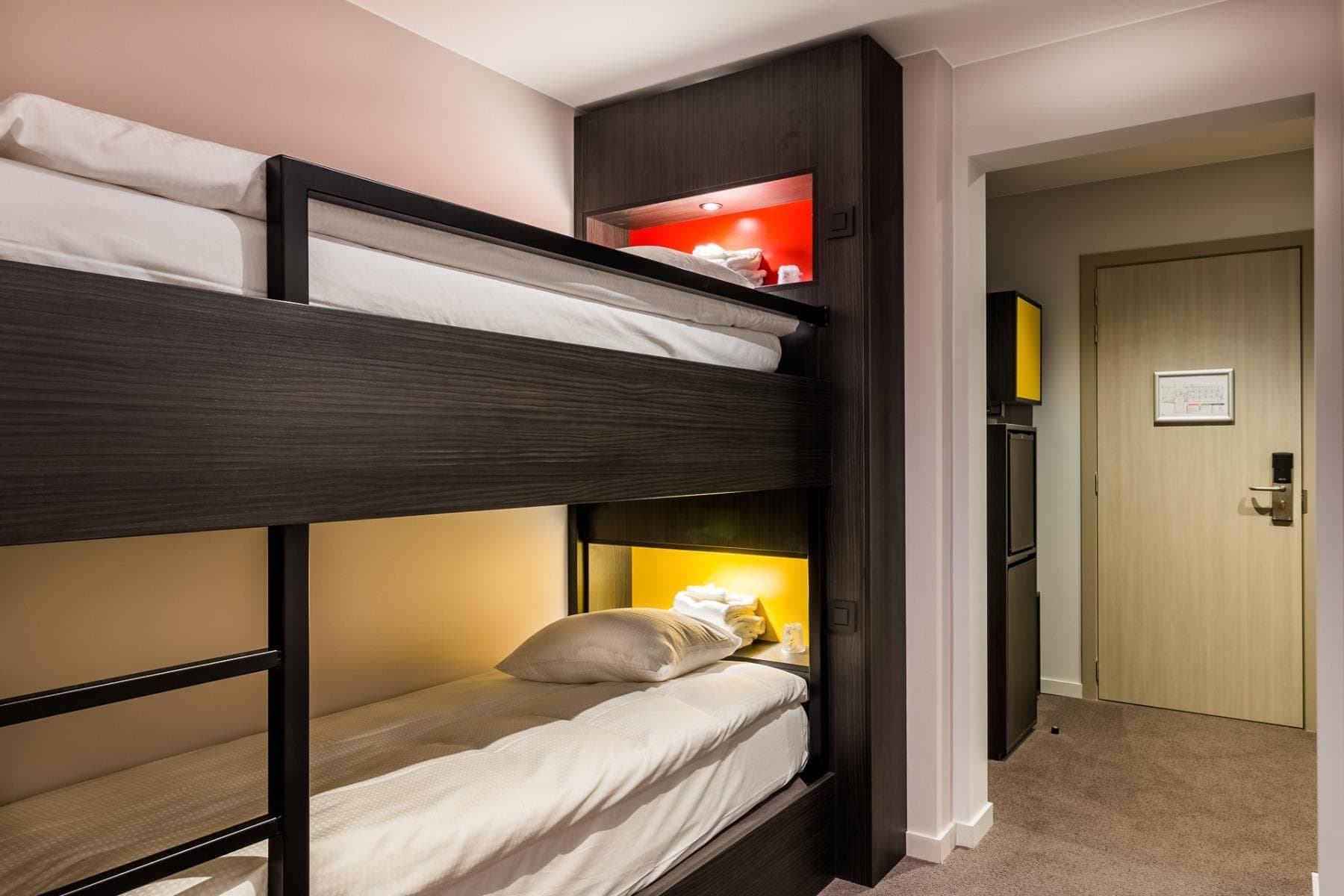Modern bunk bed bedroom with colored lighting and private entrance to hallway.