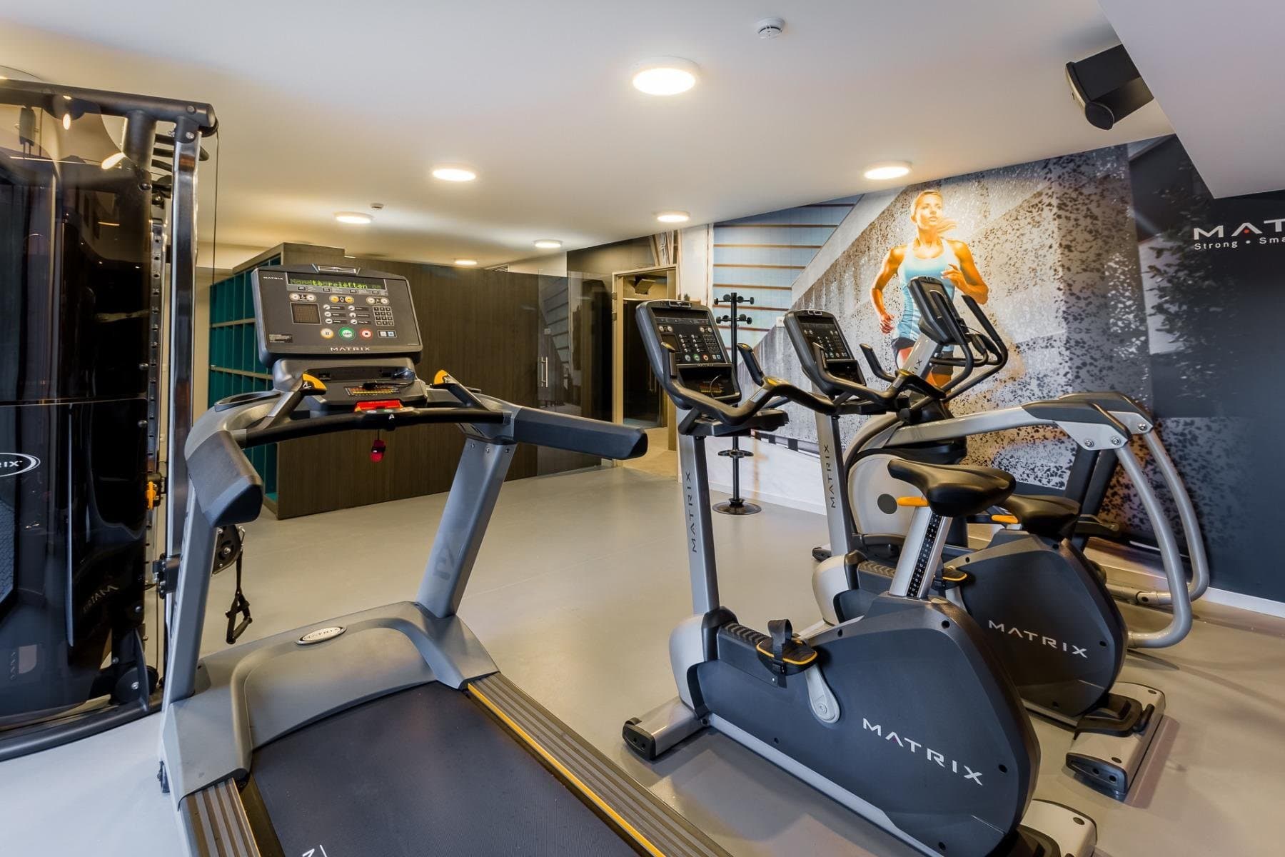 Modern fitness gym featuring Matrix cardio equipment and motivational wall artwork.