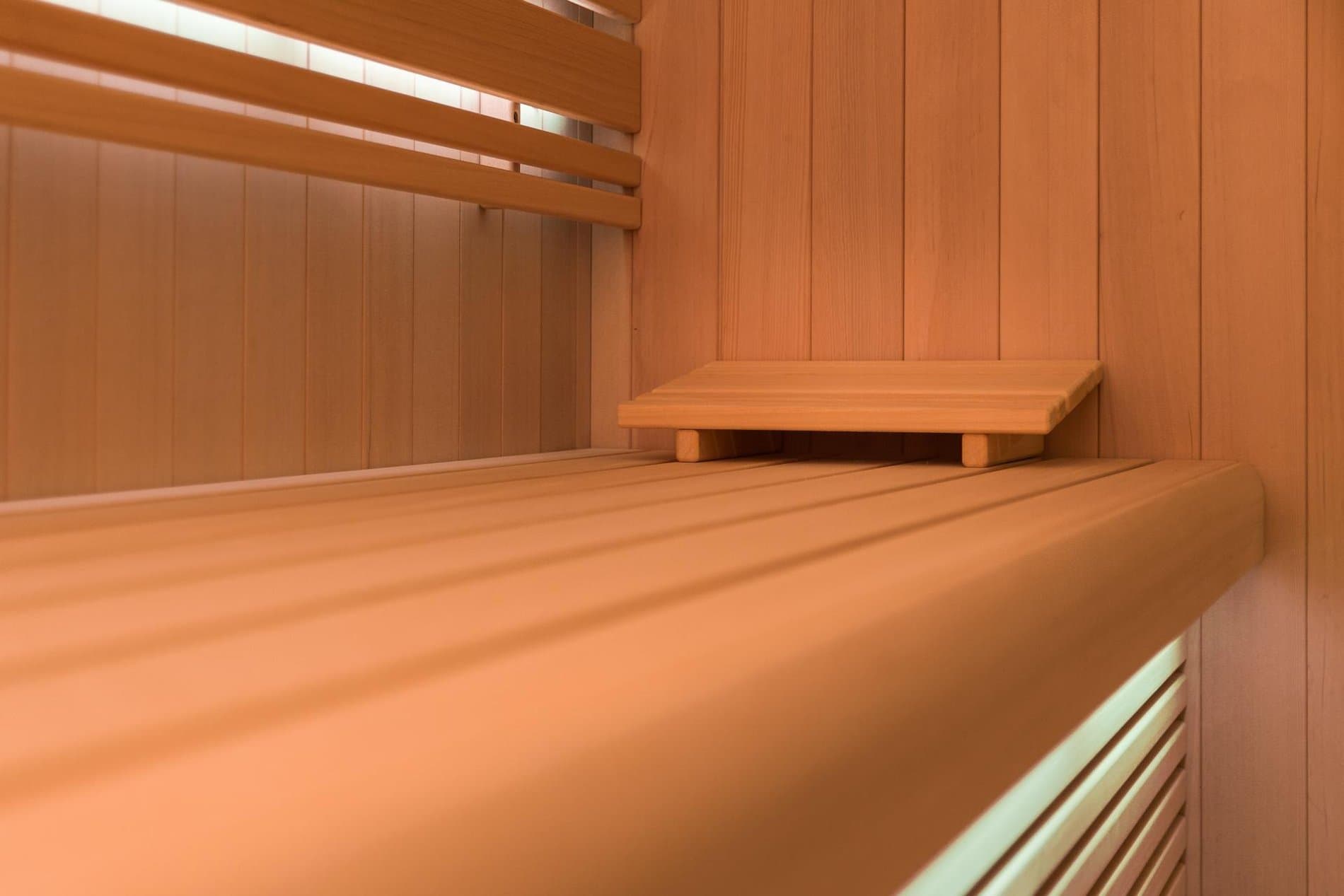 Interior of wooden sauna with bench seating and glass window panel.