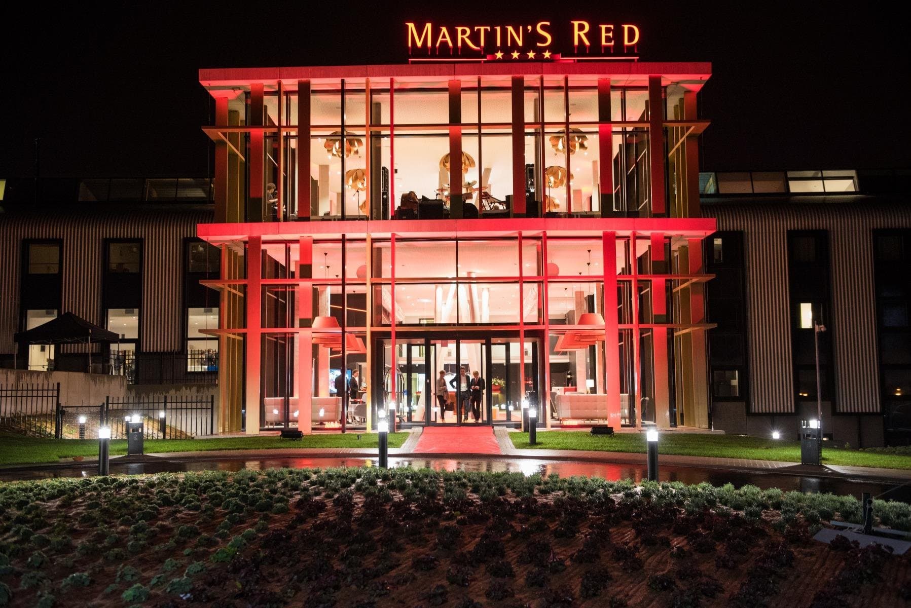 Martin's Red hotel facade at night with illuminated red framework and glowing windows.