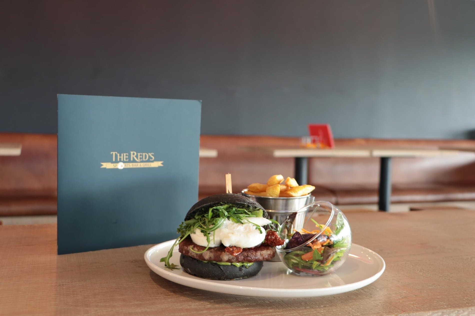 Gourmet burger meal with fries served in upscale restaurant setting with branding.
