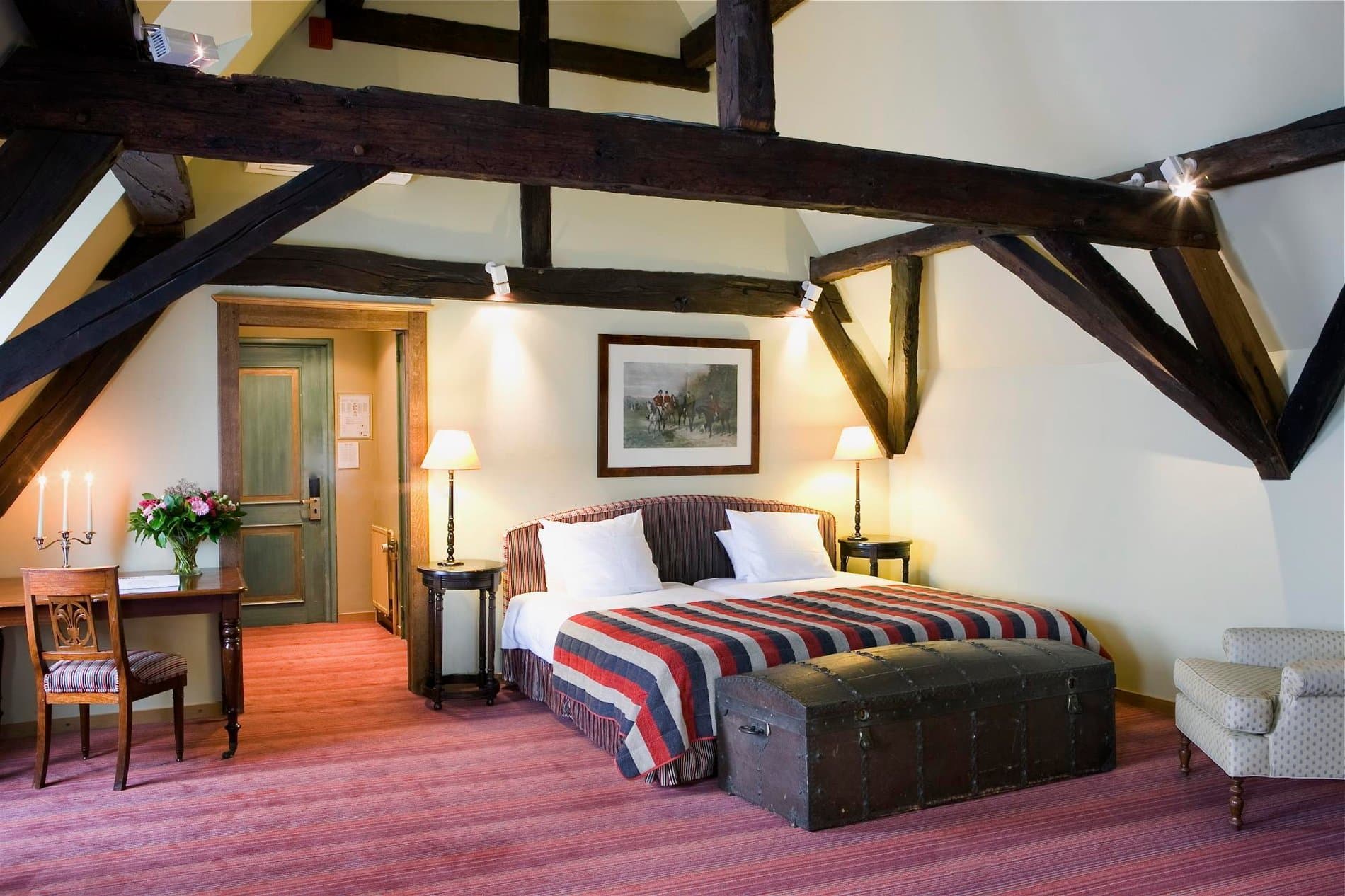 Luxurious bedroom suite with exposed beams, elegant furnishings, and period décor.