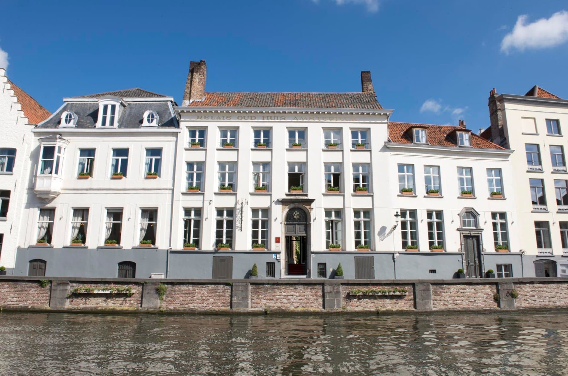 Historic waterfront townhouses with white facades and terracotta roofs facing canal.