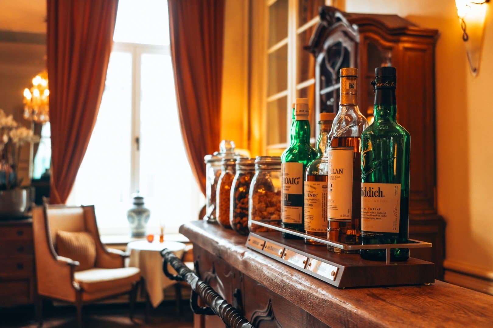 Luxury whisky bar display with premium bottles and elegant wooden furniture interior.