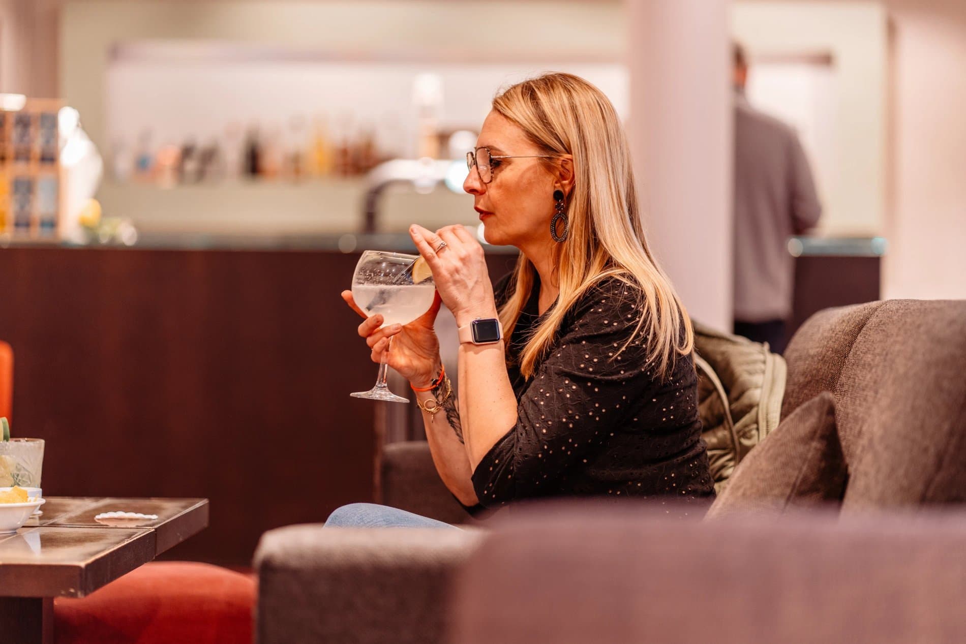 Woman enjoying a cocktail in hotel lounge bar area with comfortable seating