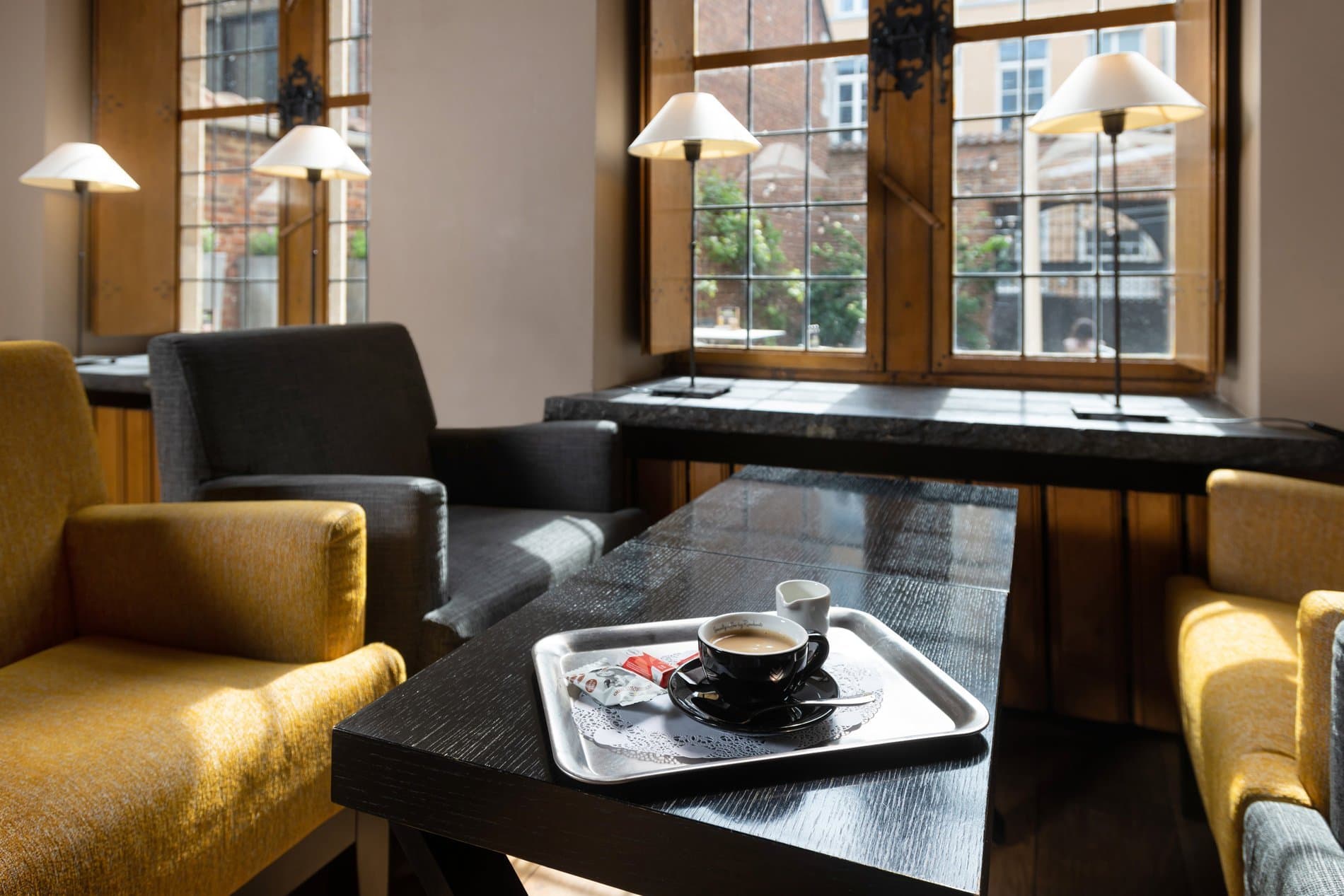 Elegant lounge space with coffee service, armchairs, and urban street views.
