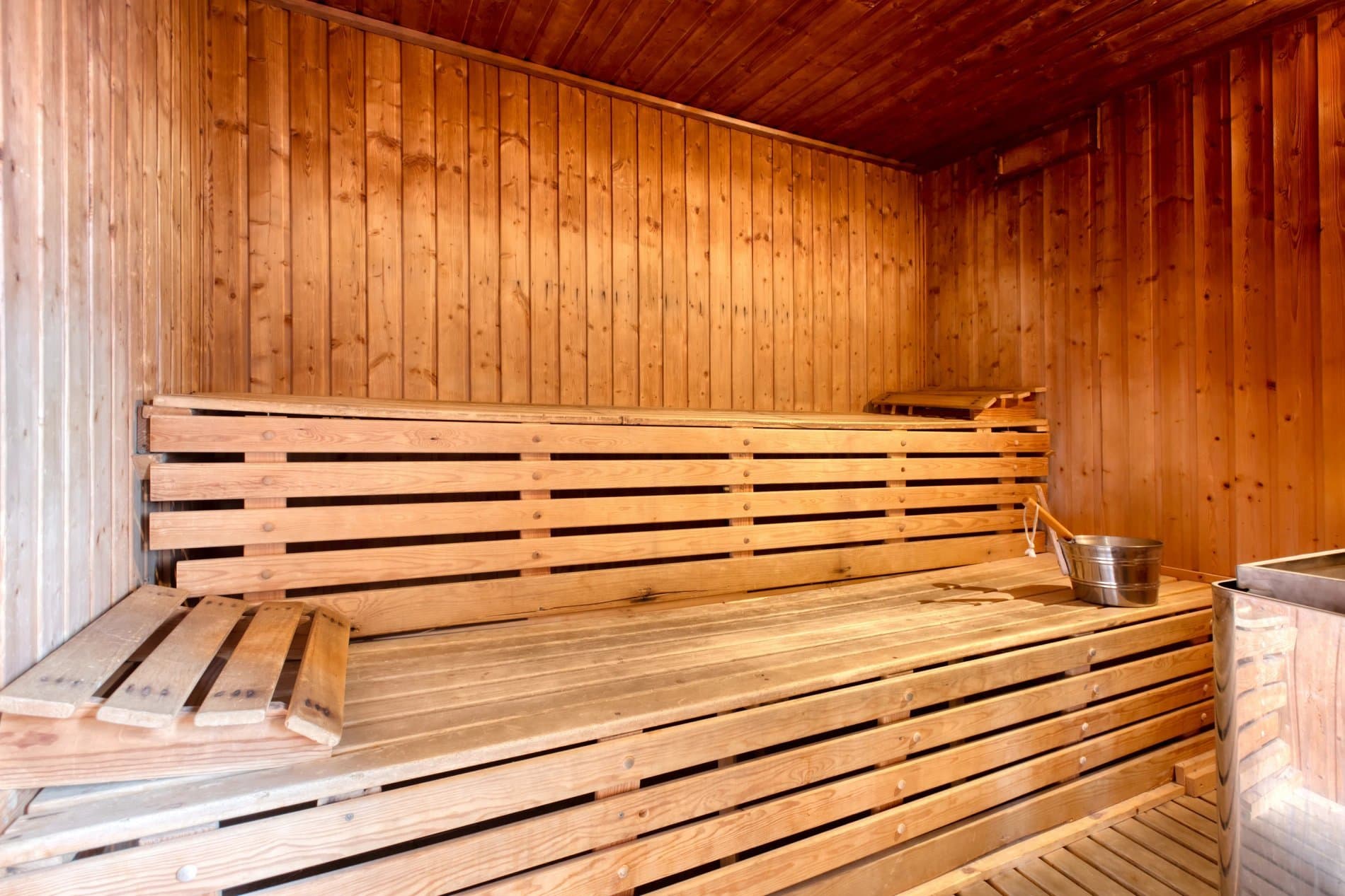 Empty wooden sauna interior with tiered benches and cedar walls throughout.