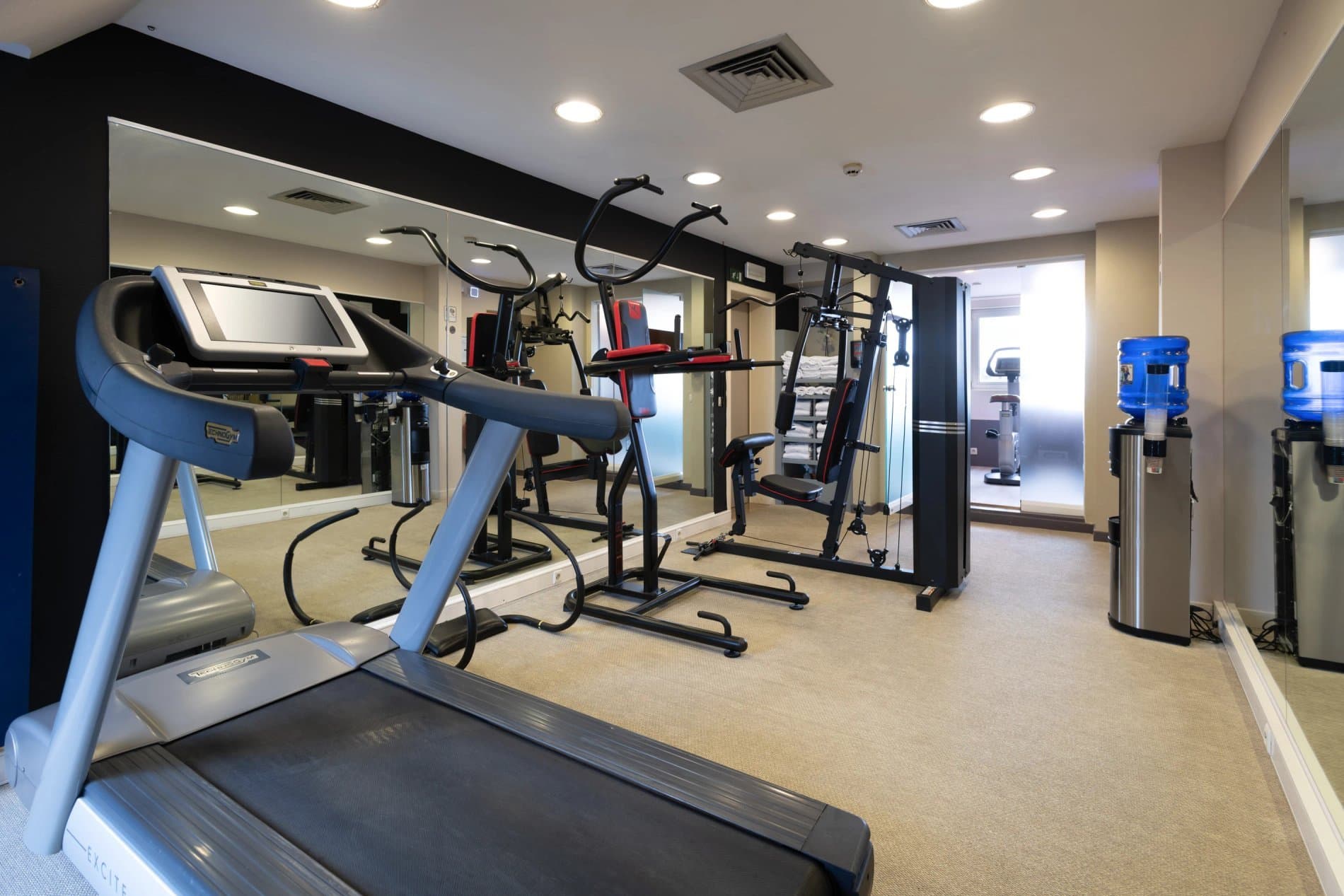 Modern fitness center with treadmill, exercise bikes, and weight machines equipment