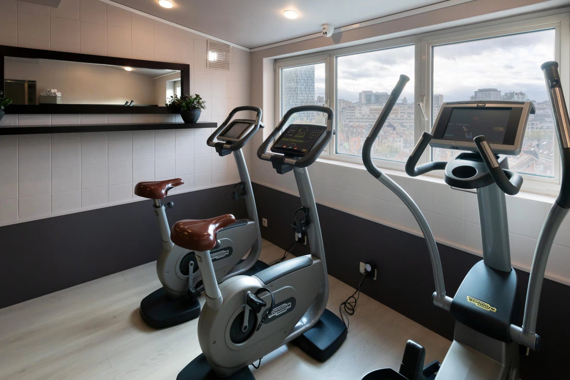 Modern fitness center with stationary bikes and cardio equipment overlooking cityscape.