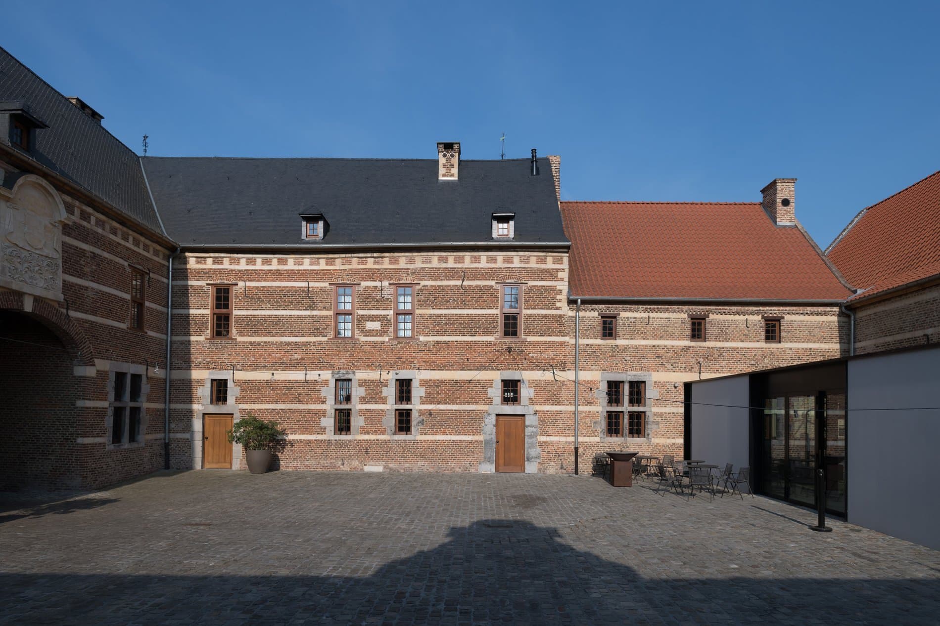 Historic brick courtyard with period architecture and terracotta roof under clear sky