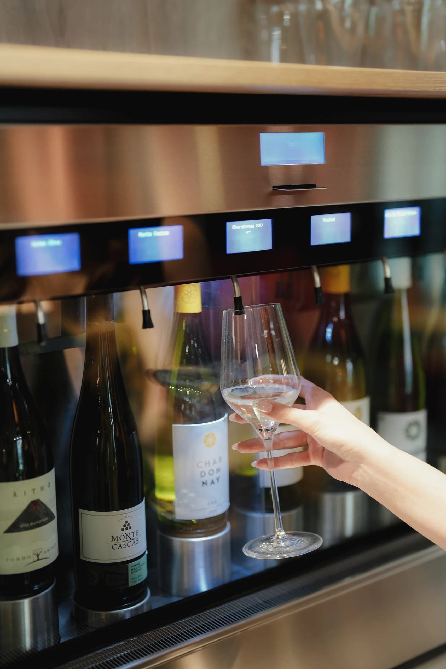 Modern wine dispensing system with glass of white wine and multiple bottle selections displayed
