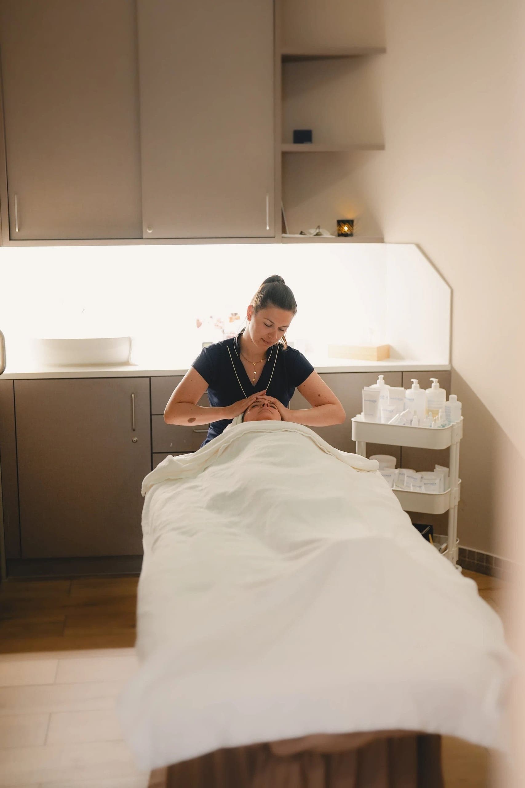 Spa therapist performing facial treatment on client in modern treatment room