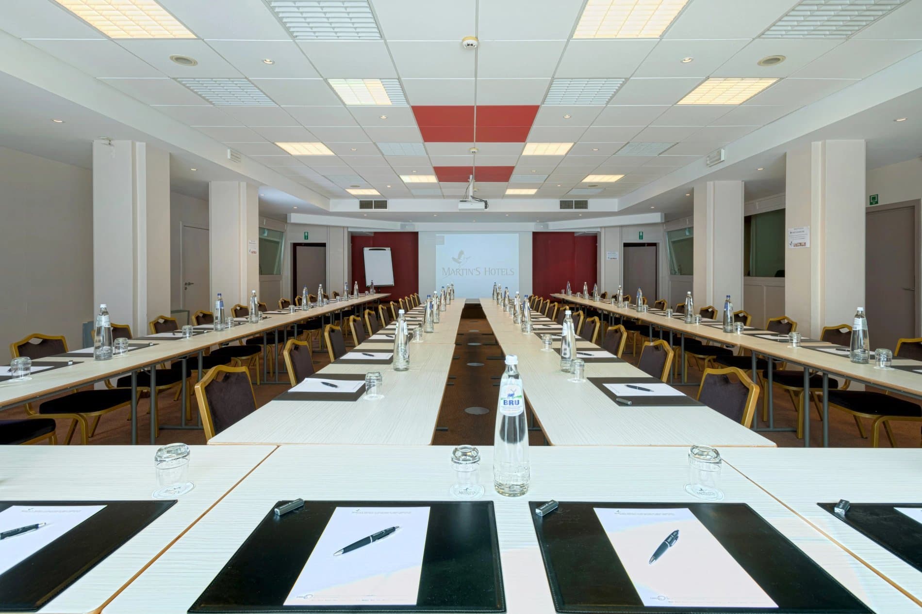 Modern hotel conference or meeting room with long tables and professional setup.