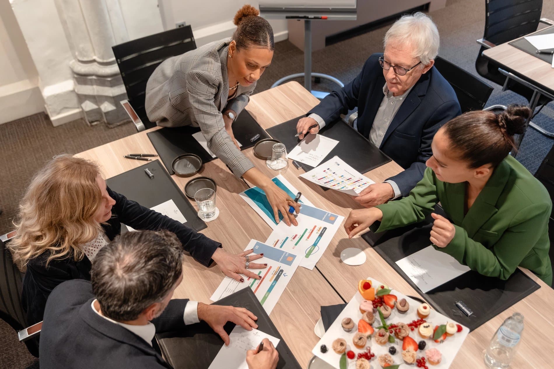 Business team collaborating over charts and food in professional meeting workspace