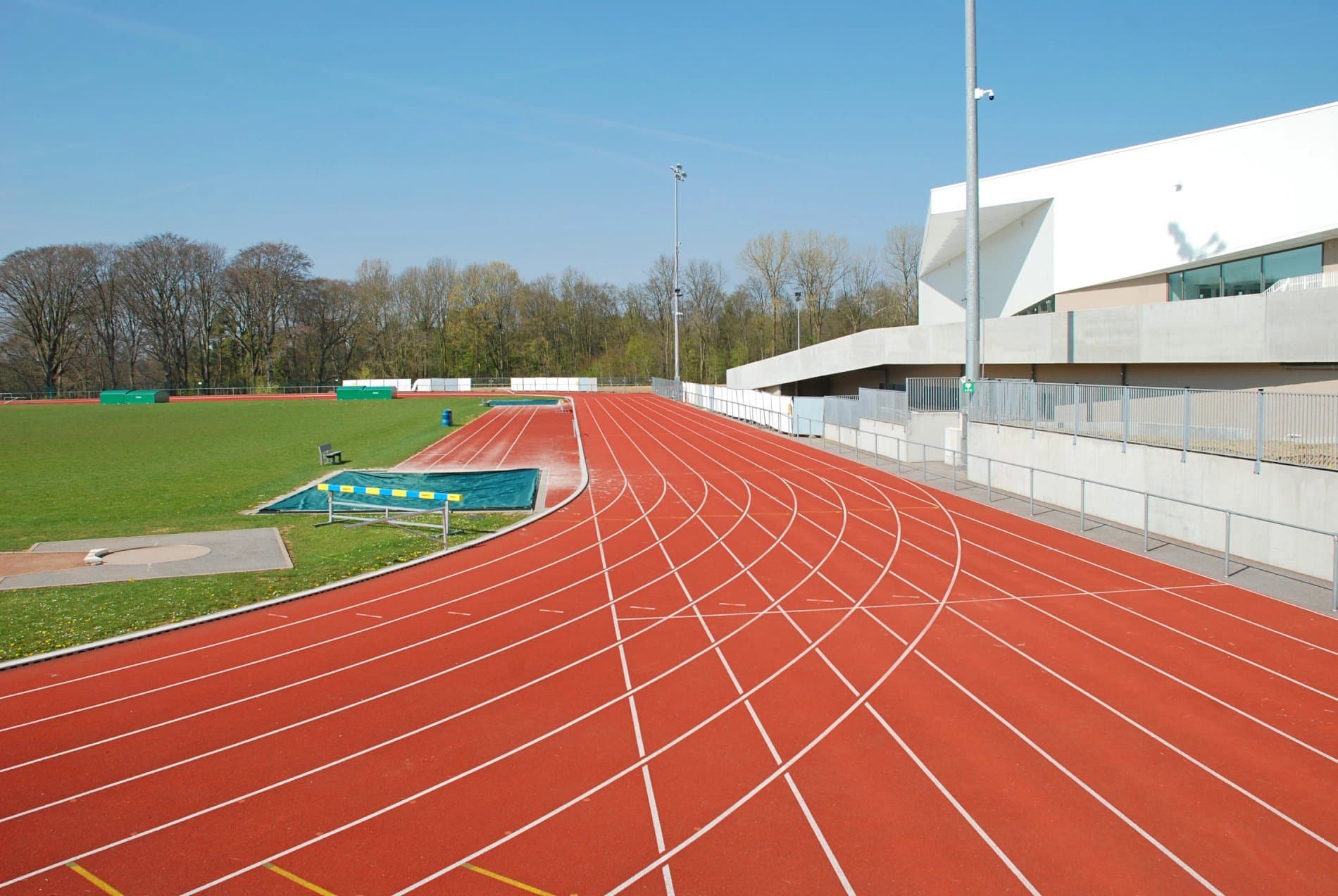 Modern athletic sports facility with red running track and white grandstand structure